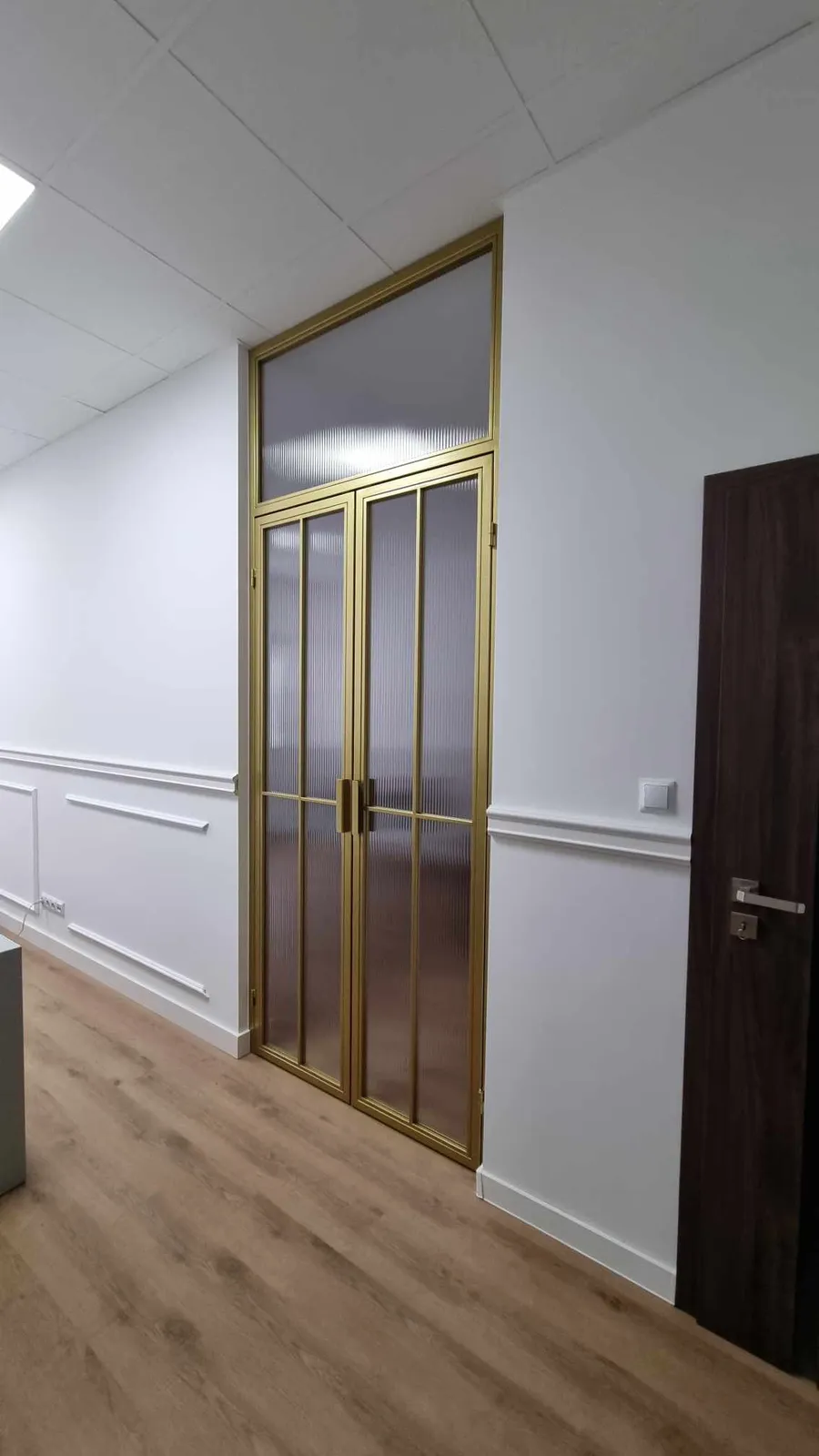 Złote drzwi loftowe z matowym szkłem w eleganckim korytarzu