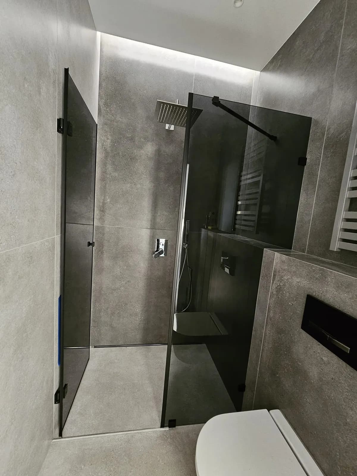 Bezramowa kabina prysznicowa walk-in z przyciemnianym szkłem w szarej łazience